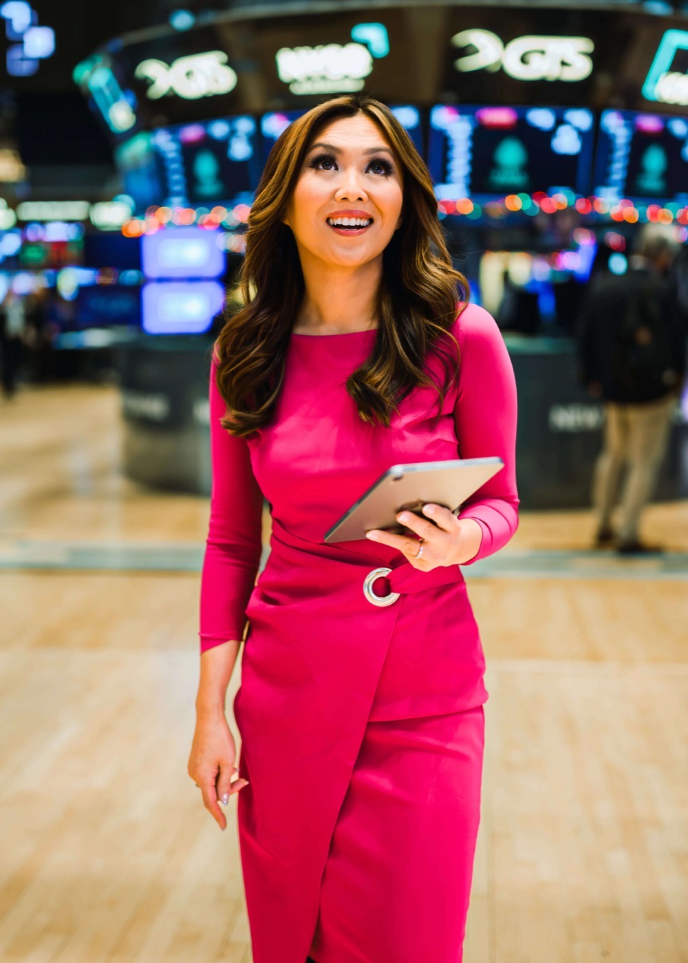 Remy Blaire walking the trading floor of the New York Stock Exchange in a bright magenta dress